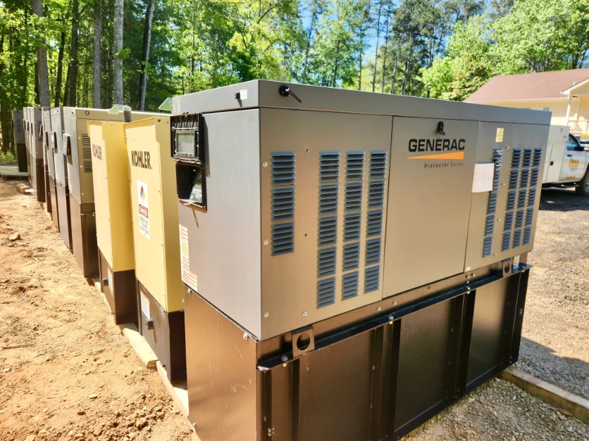 Row of Generac and Kohler commercial standby generators lined up in the equipment yard