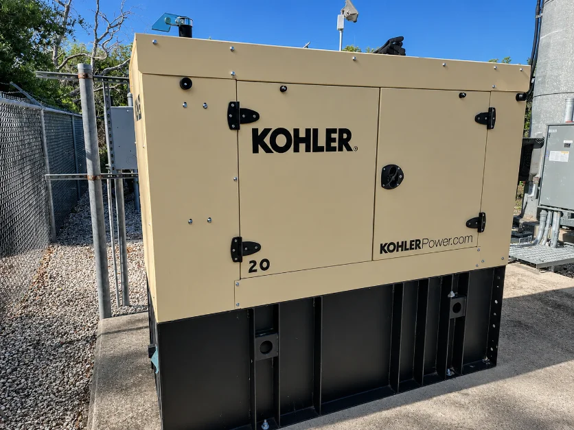 Kohler 20 kW commercial standby generator in a tan weather enclosure at a telecom site